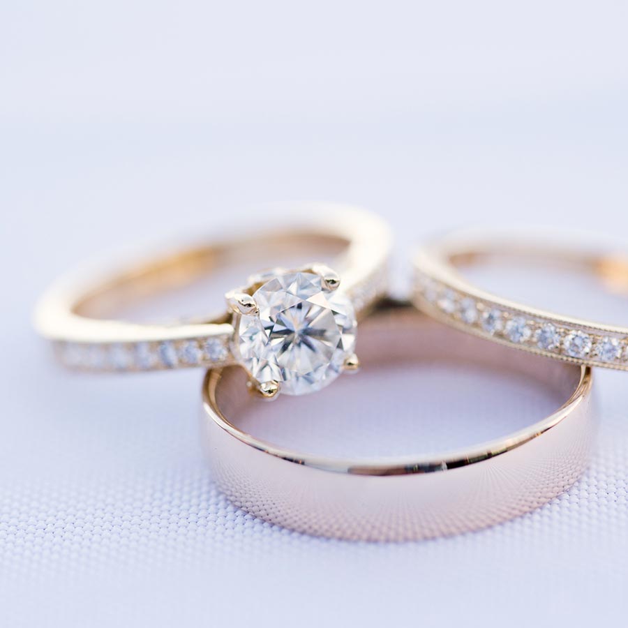 a gold wedding band with two matching diamond rings stacked off center on top